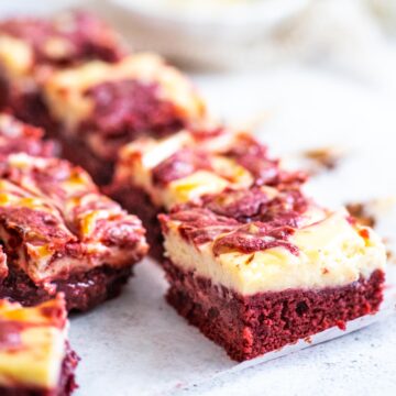 A close up of a red velvet brownie with a cheesecake layer in the foreground