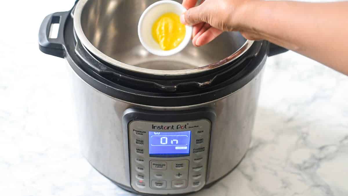 hand adding ghee to an instant pot