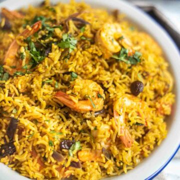 Shrimp and rice with coriander and raisins on a white plate