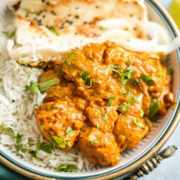 Chicken karahi served in a brass bowl with naan and rice