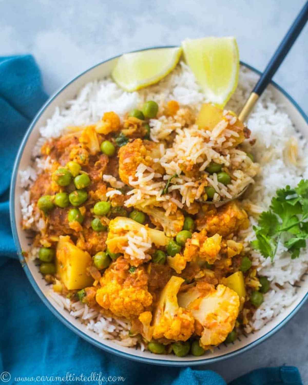 A bowl of cauliflower, peas and potatoes curry, served over rice