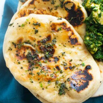 Naan bread stacked on a kitchen towel