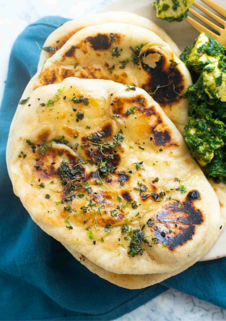 Naan bread stacked on a kitchen towel