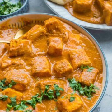 bowl with paneer curry garnished with chopped cilantro