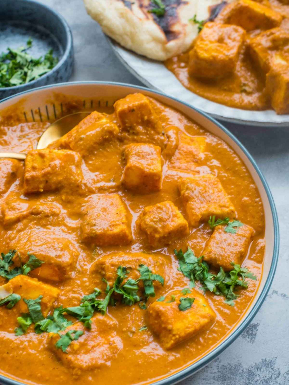 A bowl of paneer tikka masala with a coriander garnish