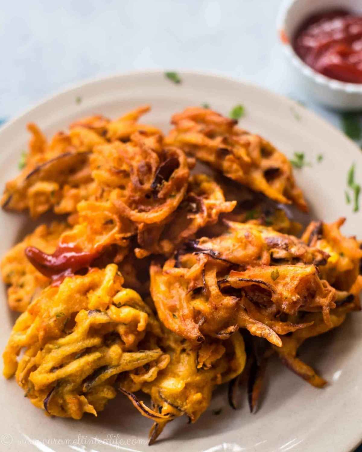 Vegetable pakoras sitting on a plate with ketchup
