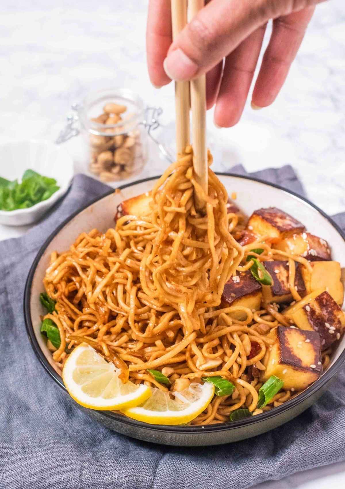 Noodles in a bowl being lifted with chopsticks
