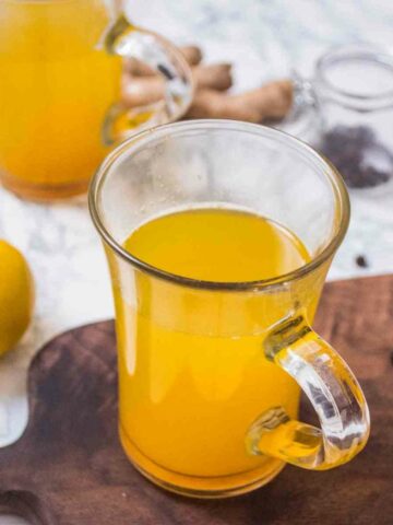 A glass mug with ginger lemon drink in the foreground