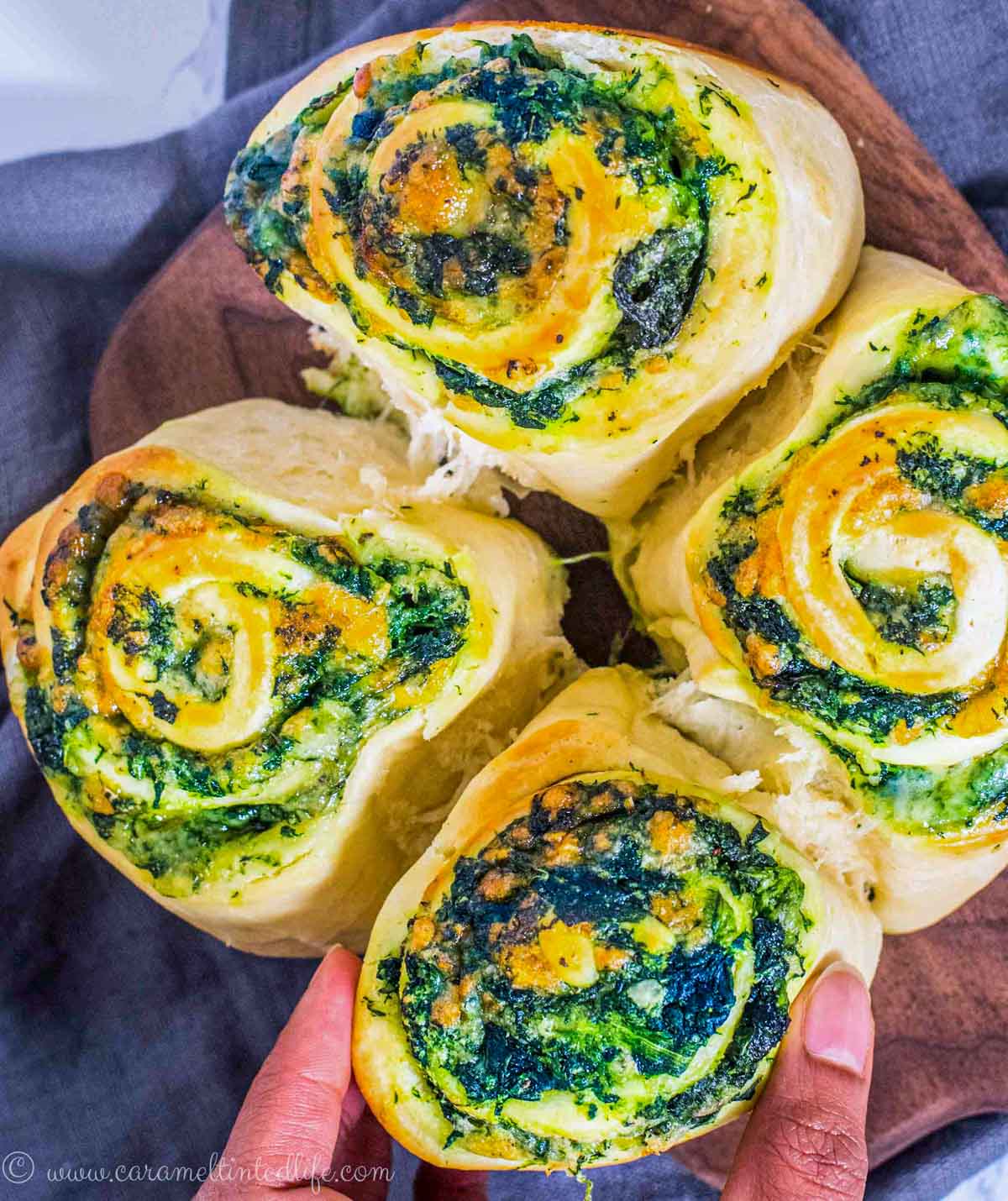 Fingers pulling apart a spinach and cheese stuffed bread roll