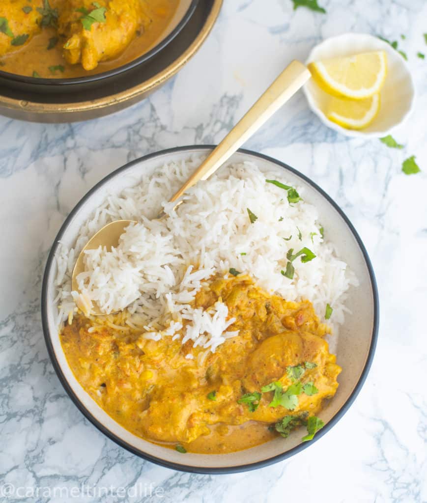 CHicken Curry served in a bowl alongside white basmati rice