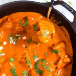 Butter Chicken in a golden spoon held by a hand