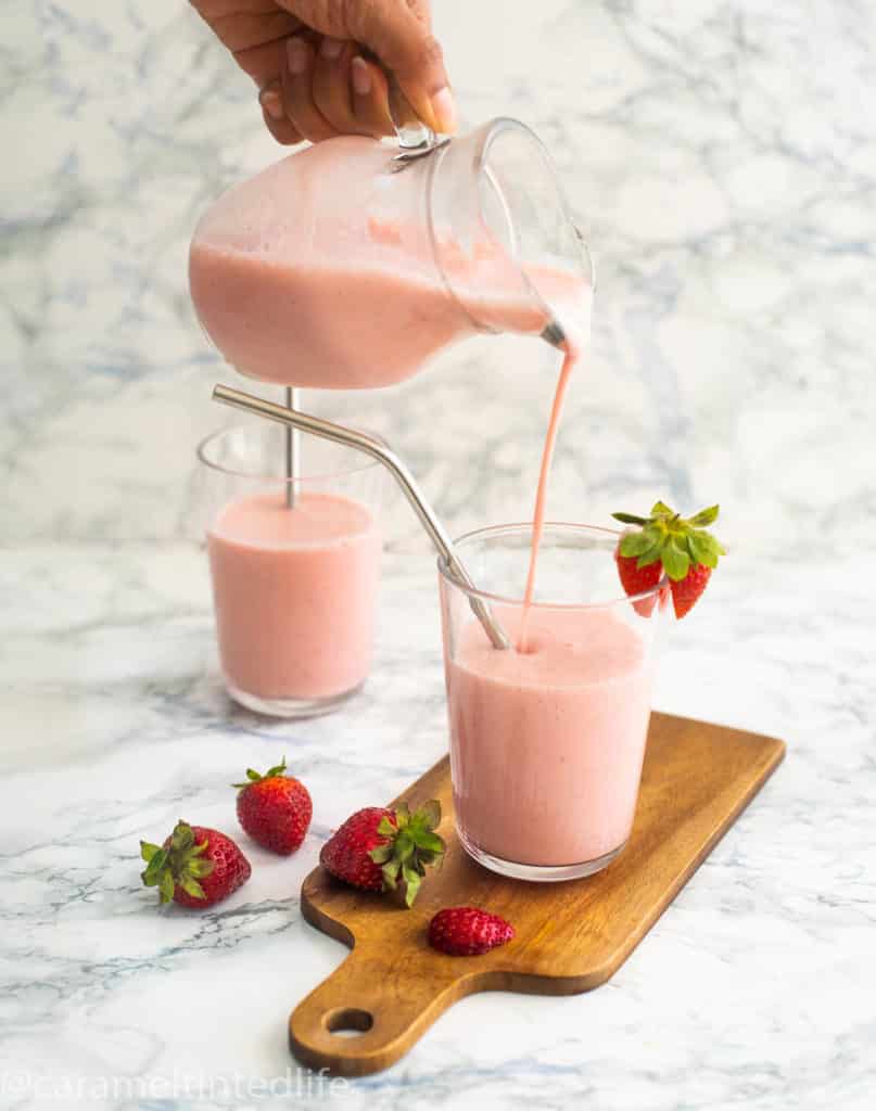 Strawberry lassi poured from a jug into a glass