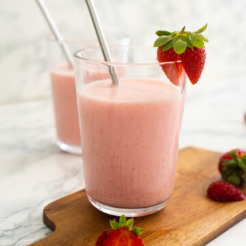 Strawberry lassi in a glass with a steel straw