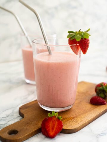 Strawberry lassi in a glass with a steel straw