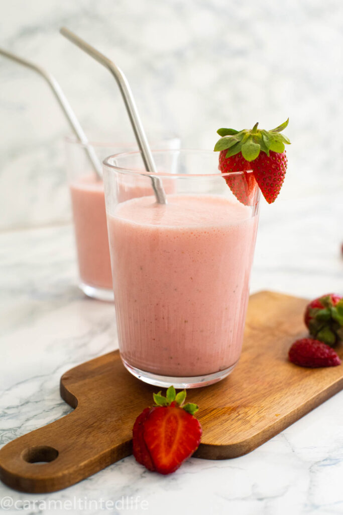 Strawberry lassi in a glass with a steel straw