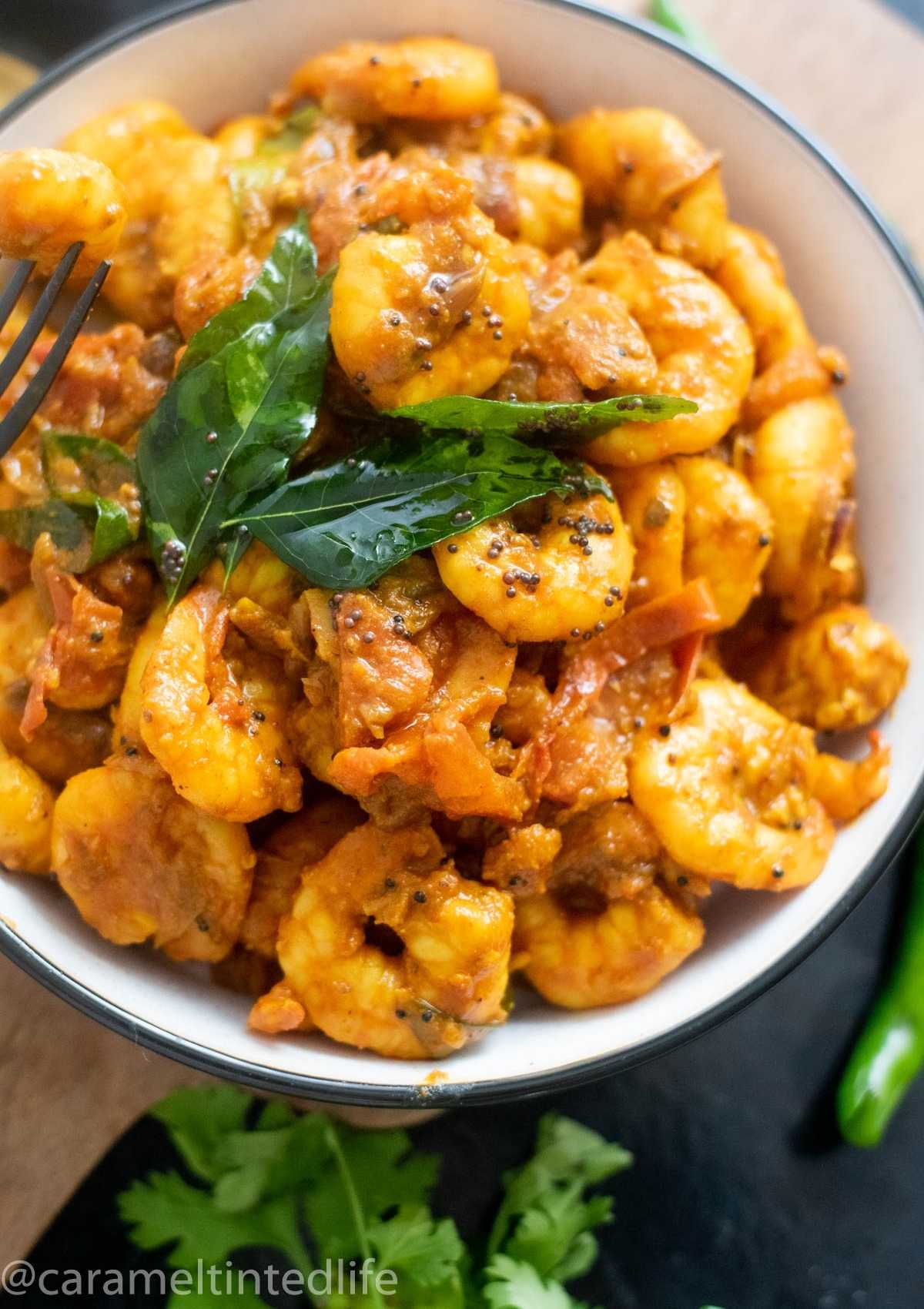 A close-up of shrimp masala tempered with curry leaves in a bowl