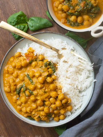 Coconut chickpea curry with spinach in a bowl with rice and a fork