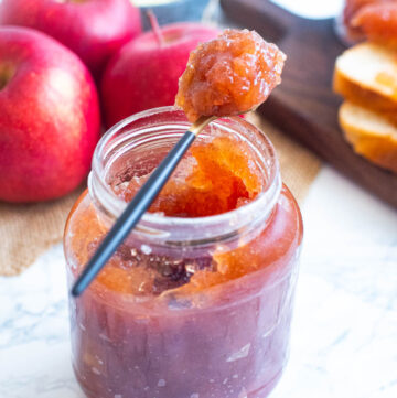Apple jam in a glass jar, with a small teaspoon of jam