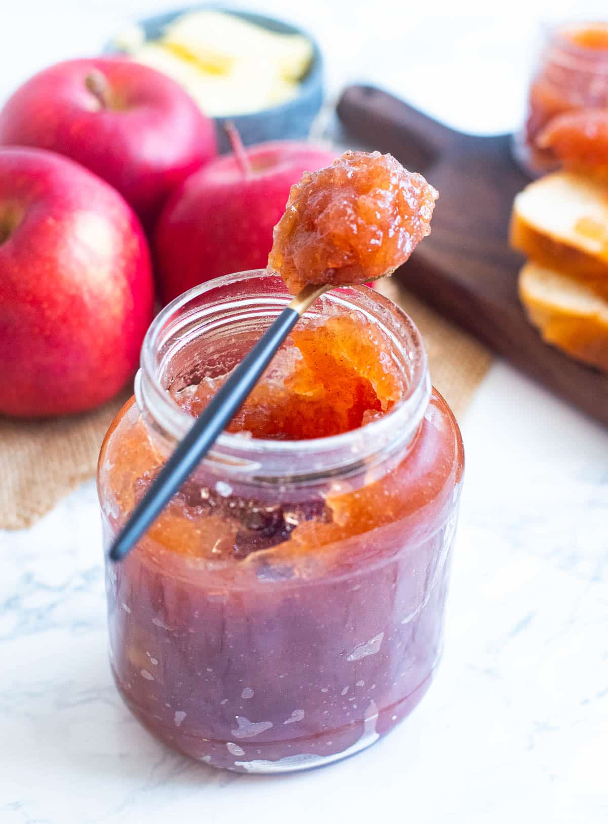 Apple jam in a glass jar, with a small teaspoon of jam