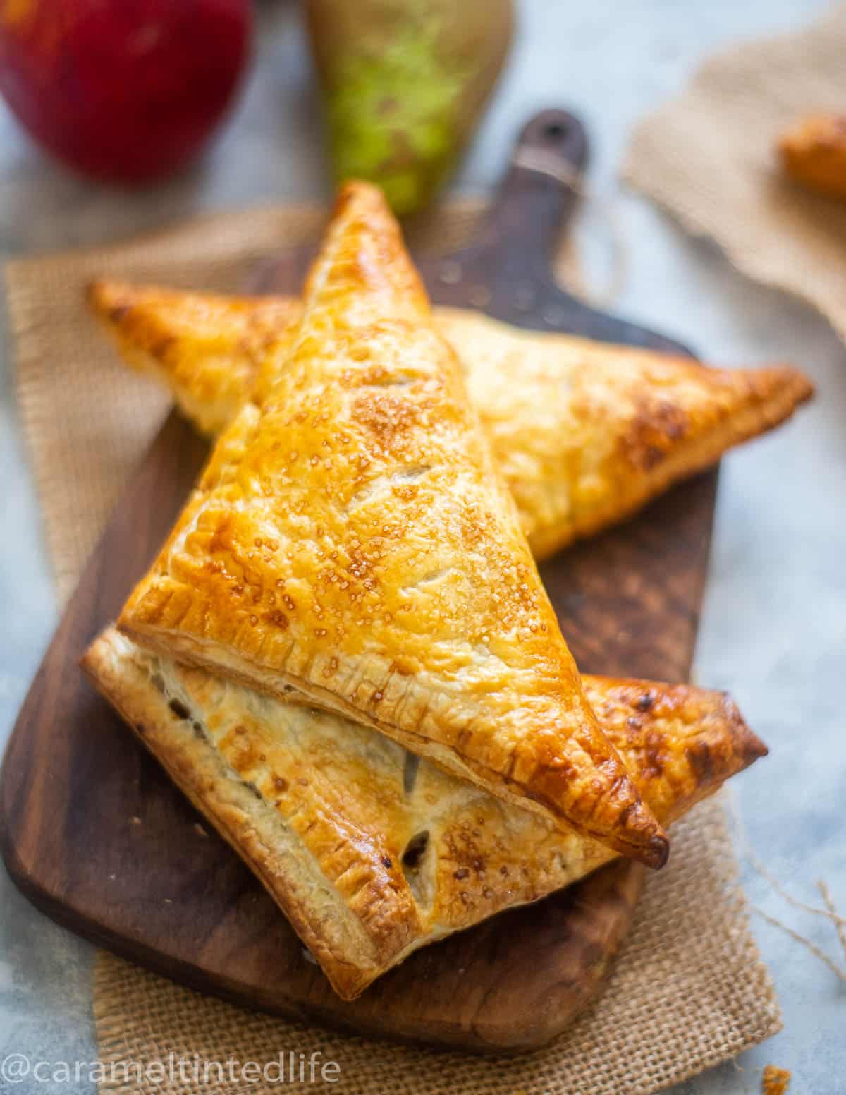 Pear adn dapple turnovers stacked on a wooden board