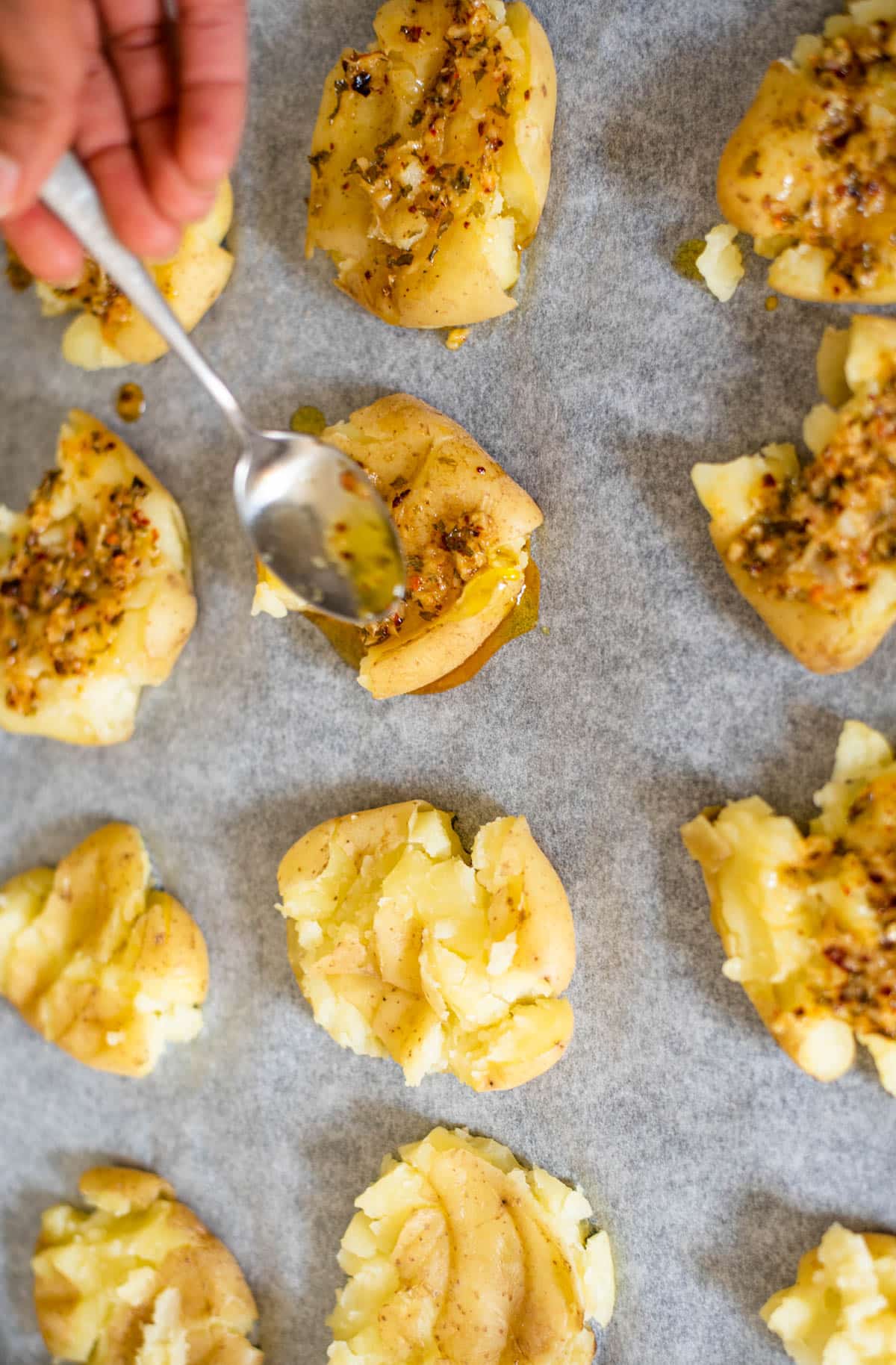 Pour melted butter with grated garlic, chopped parsley and thyme over smashed potatoes