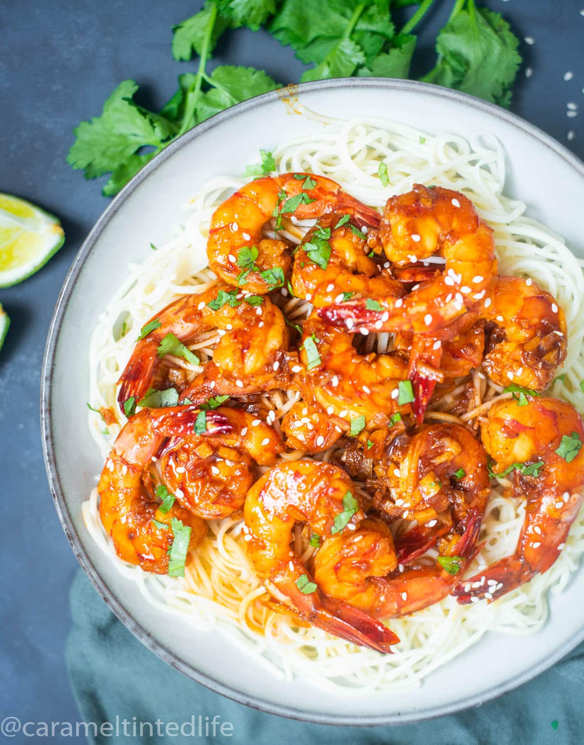 Honey garlic prawns on noodles on a blue background