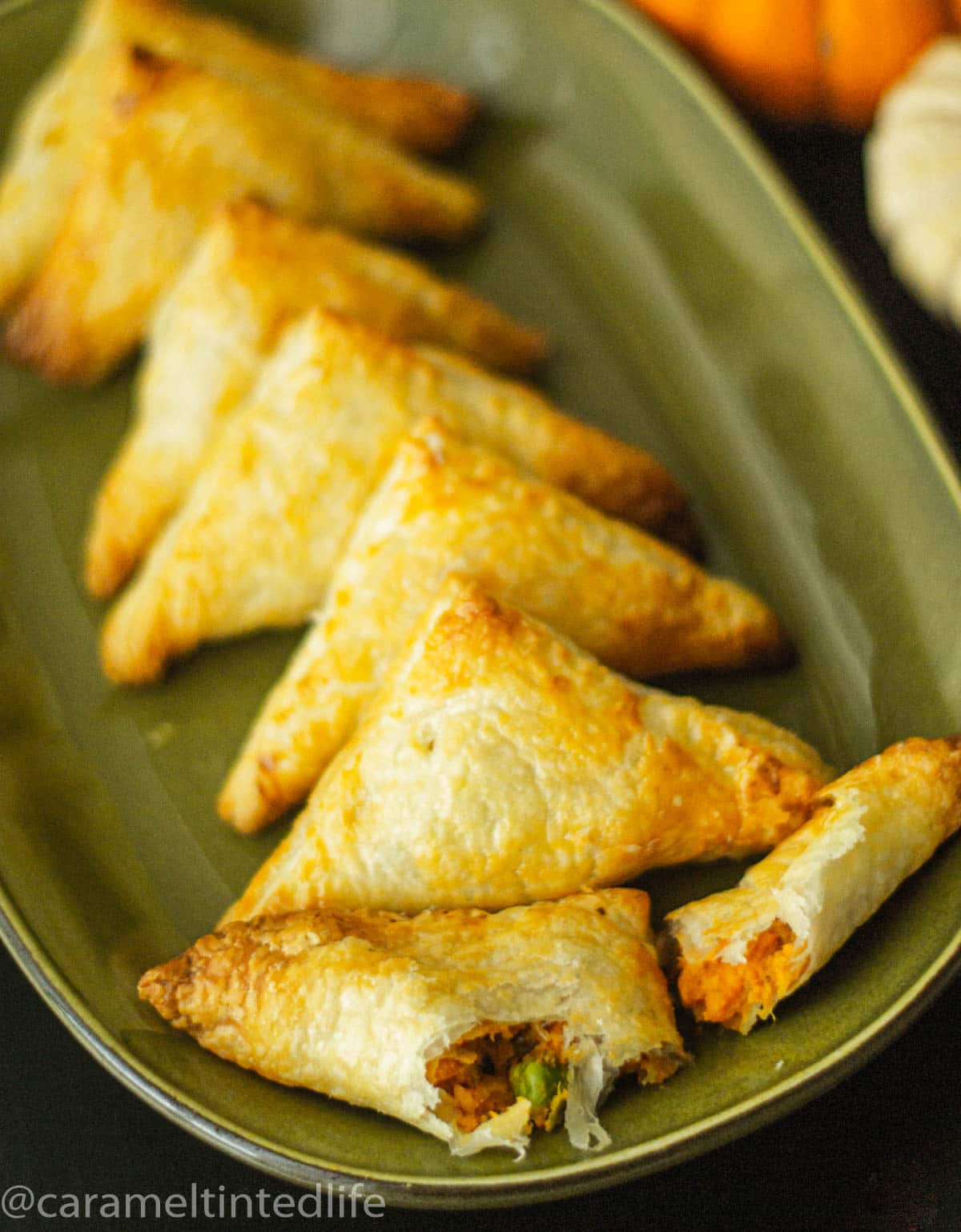 Puff pastry samosas arranged on a green plate