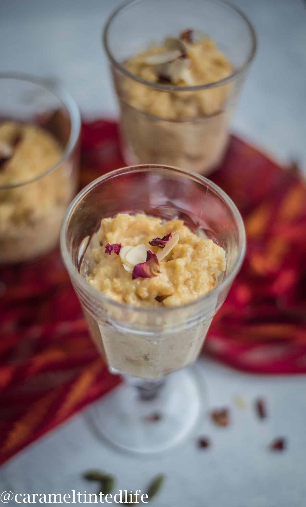 Kheer served in a decorative glass with two glasses in the background 