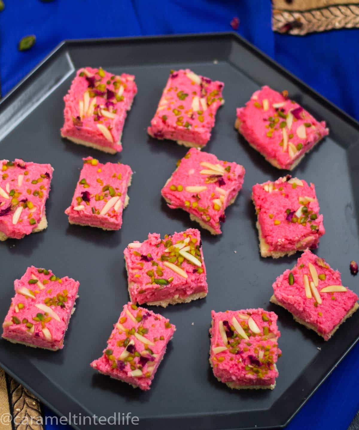 Squares slices of rose kalakand on a black tray