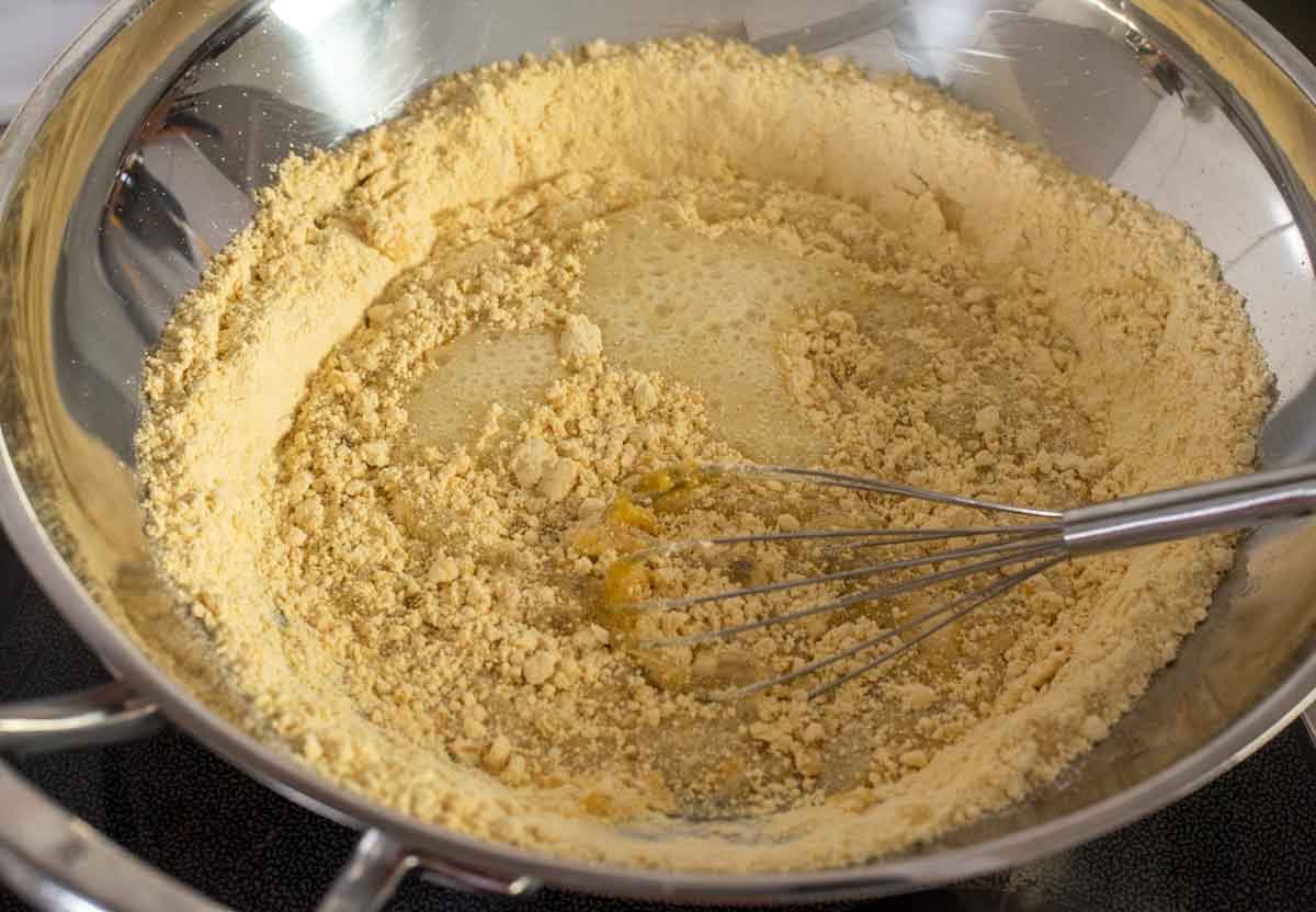 Adding seived chickpea flour to a hot sugar syrup mixture on the stovetop