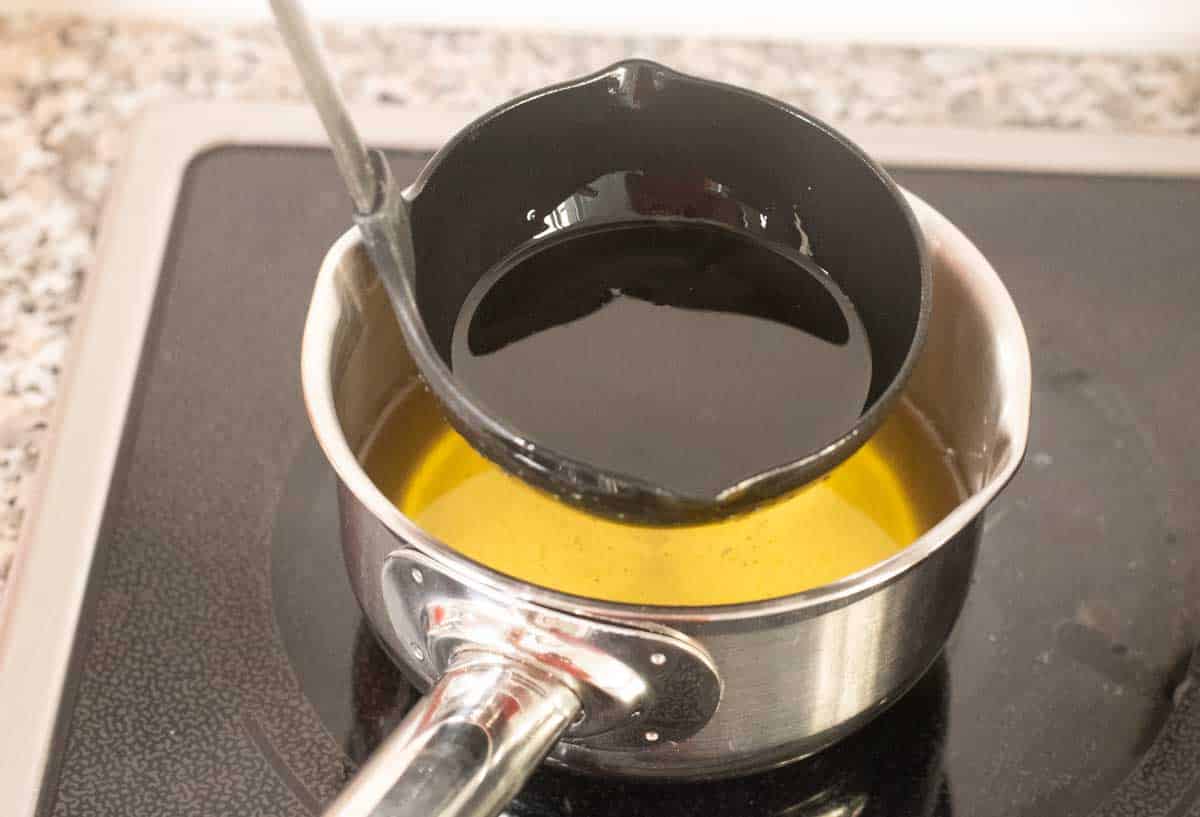 Ladle of hot ghee and oil mixture on the stovetop