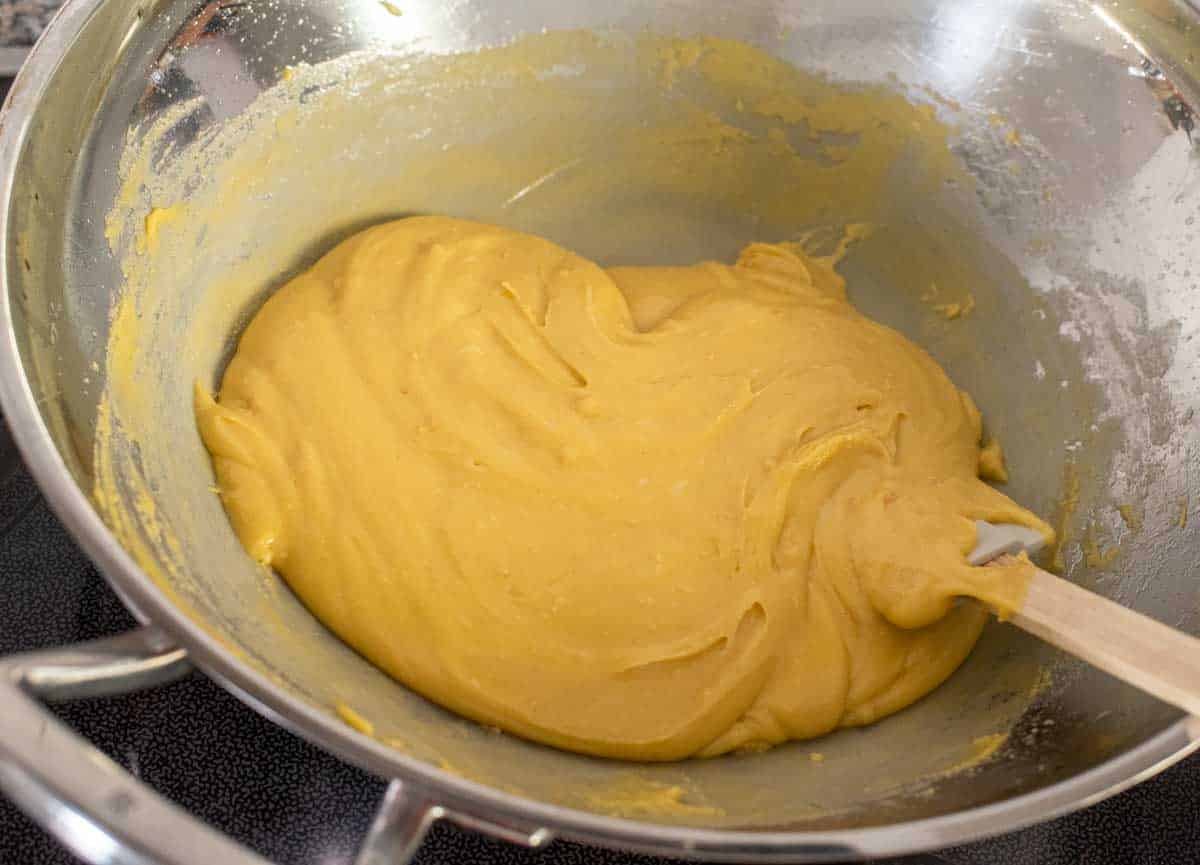 Batter of chickpea flour, after it has absorbed oil and ghee, in a steel wok with a spatula