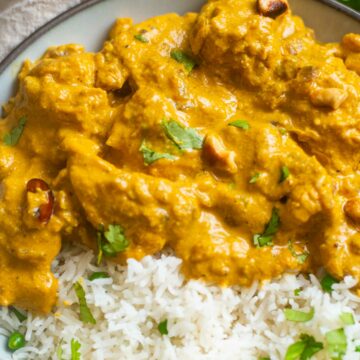 Close-up of chicken korma in a bowl with rice and chopped cilantro garnish