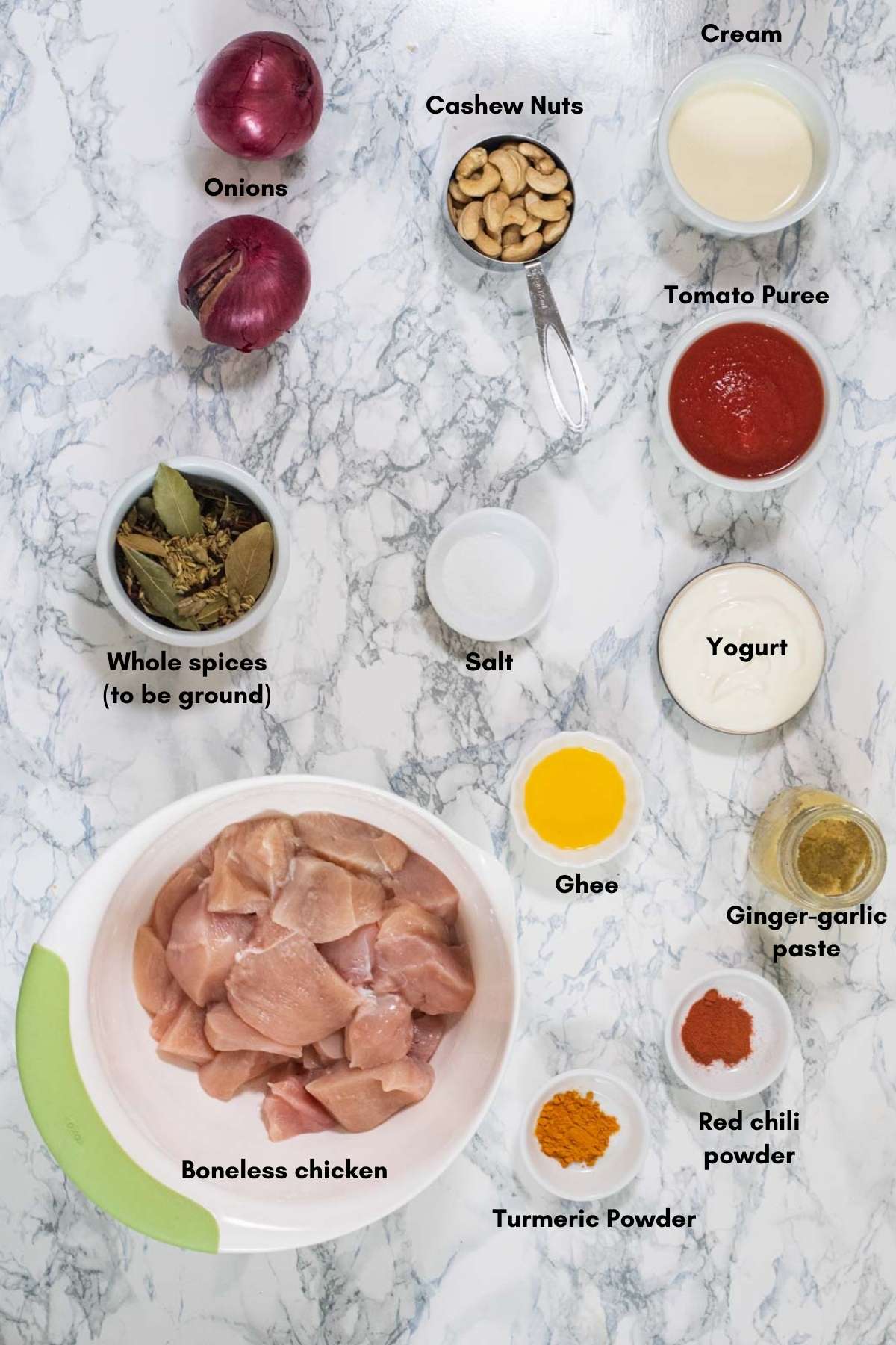 Ingredients used to make chicken korma place on a white background 
