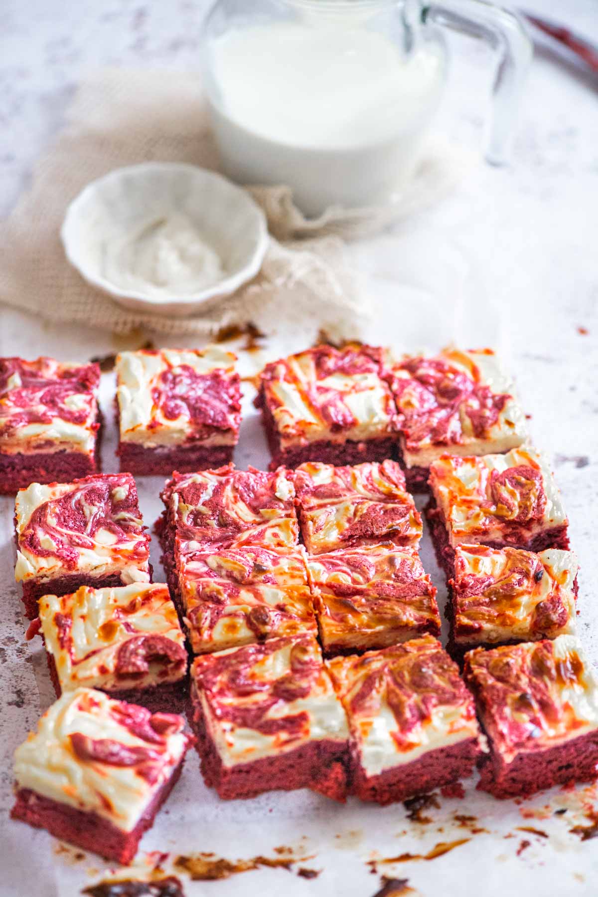 Pices of red velvet and cheesecake brownies on a white surface