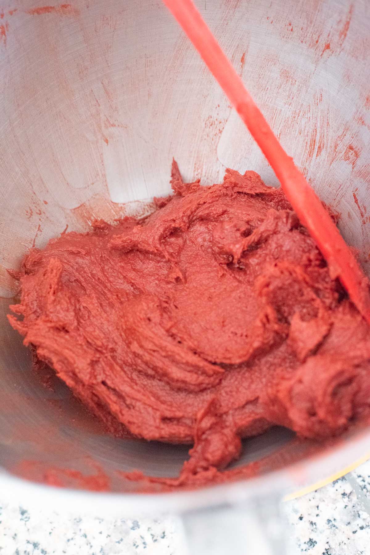 Red batter in the bowl of a stand mixer