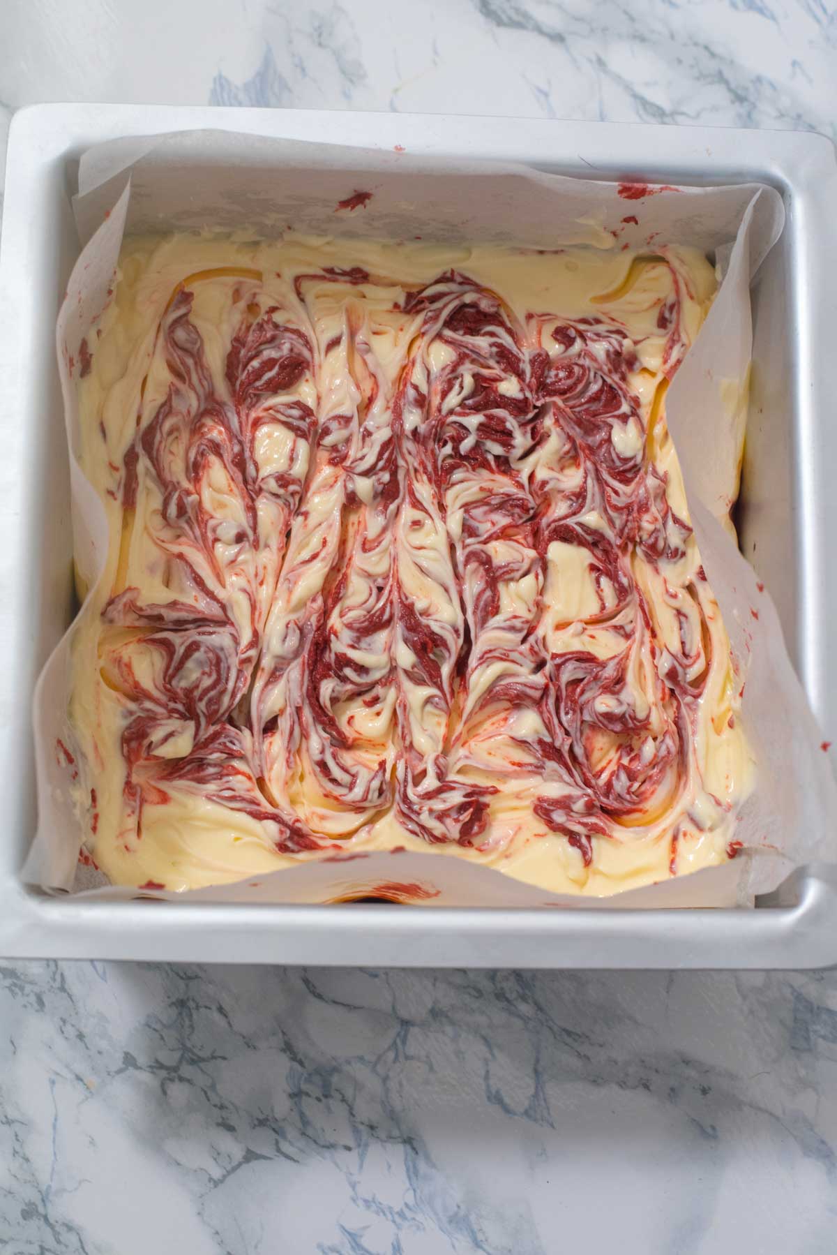 Top view of cake with cake batter with red swirls in it