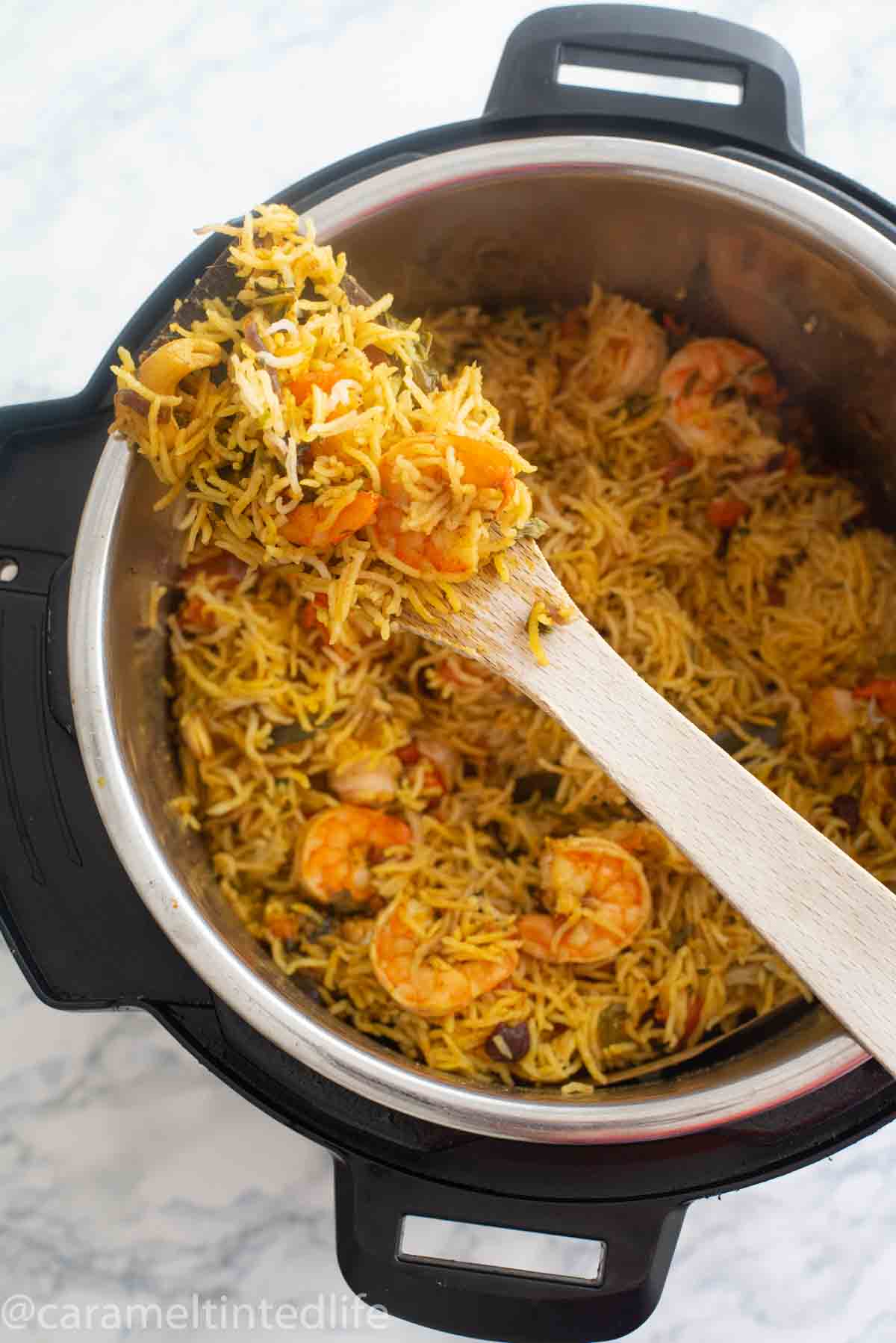 Shrimp biryani on a wooden ladle resting on an Instant Pot 