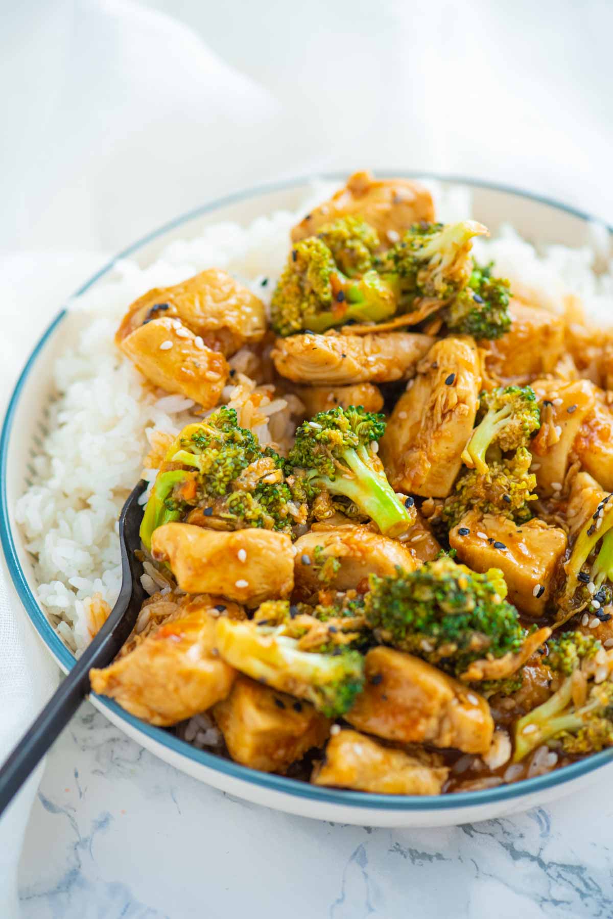A bowl of chicken and Broccoli with white rice and a fork