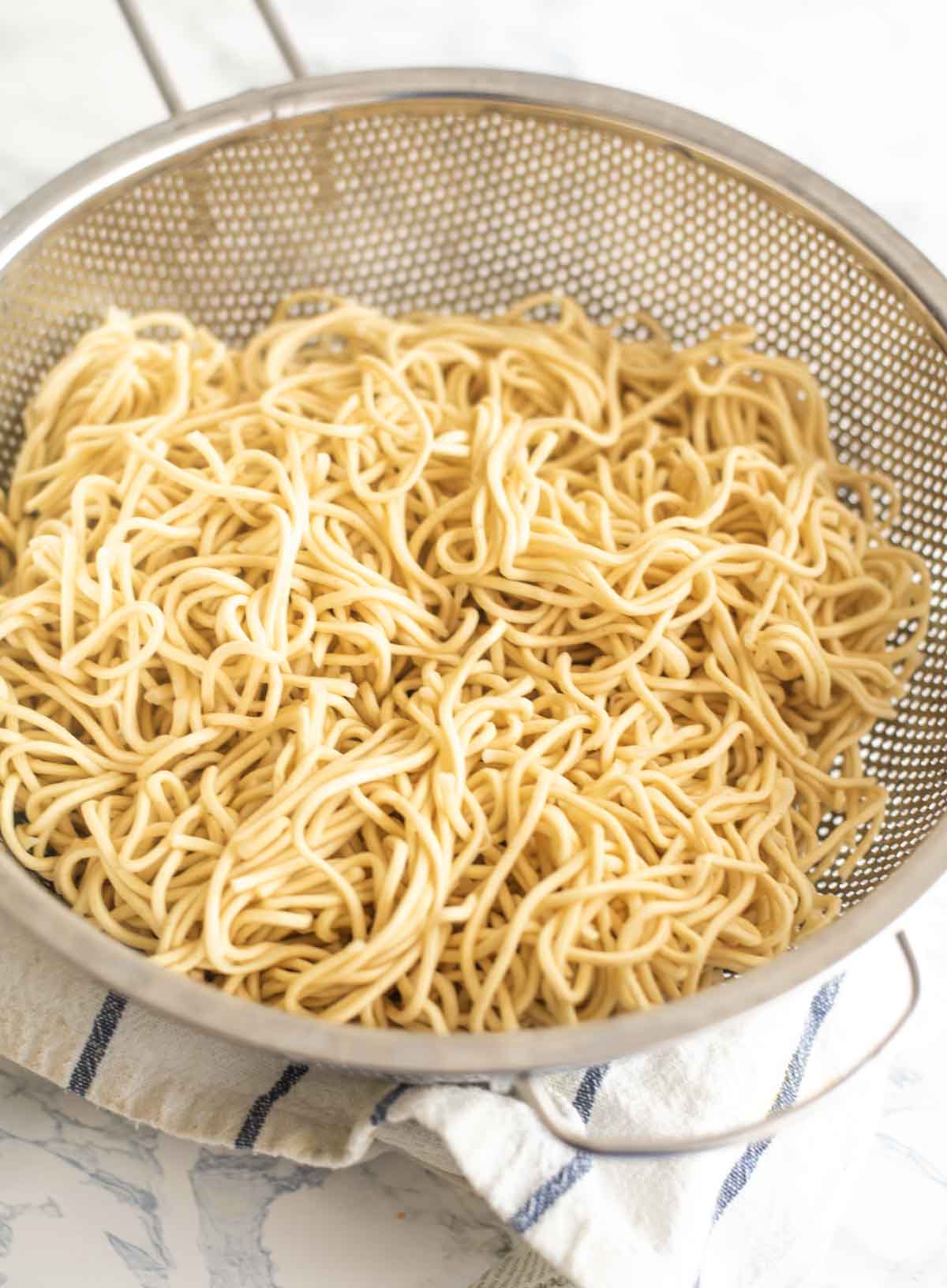 Cooked chow mein noodles in a strainer