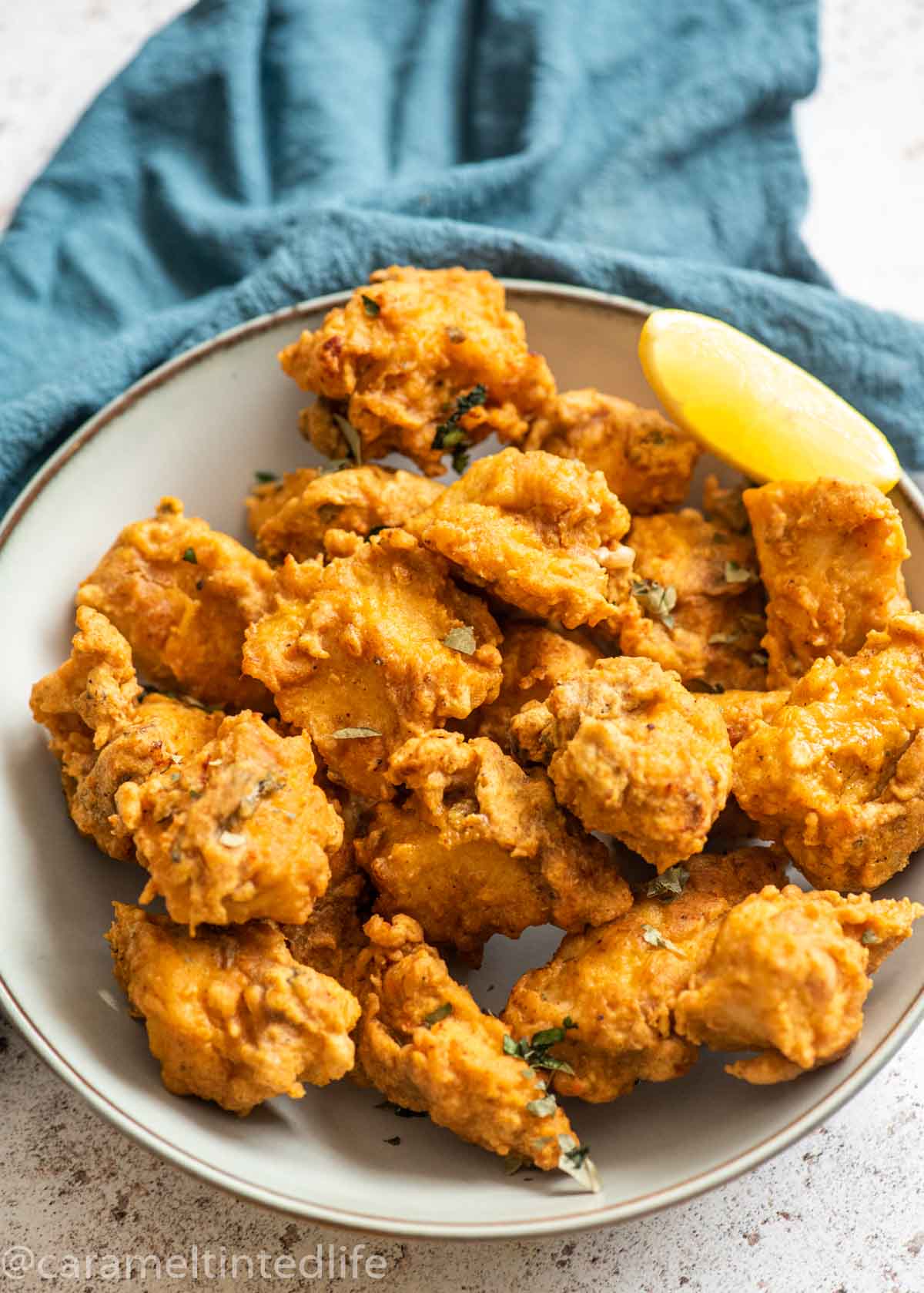 Chicken Pakoras in a large bowl with a wedge of lemon