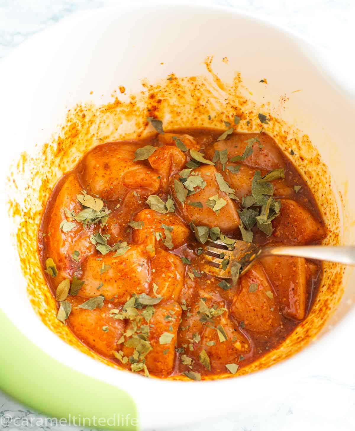 Adding dried curry leaves to the chicken marinade