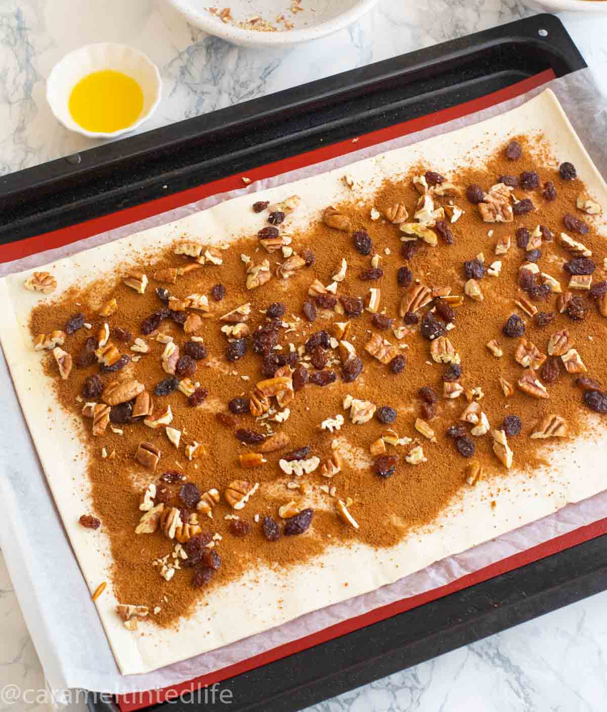 Sheet of puff pastry topped with brown sugar, raisins and nuts 