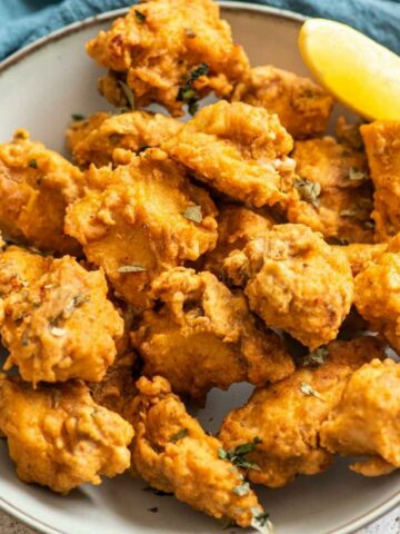 a bowl of chicken pakoras with lemon wedge
