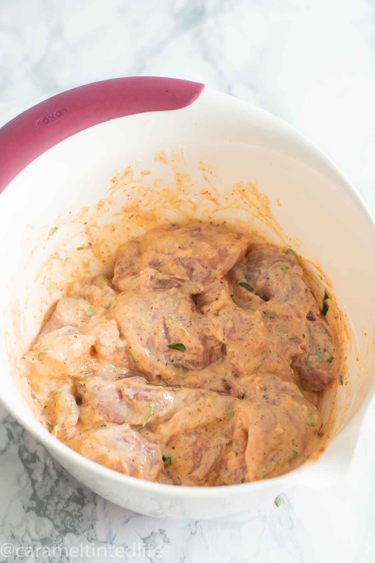 chicken coated in marinade in a large mixing bowl