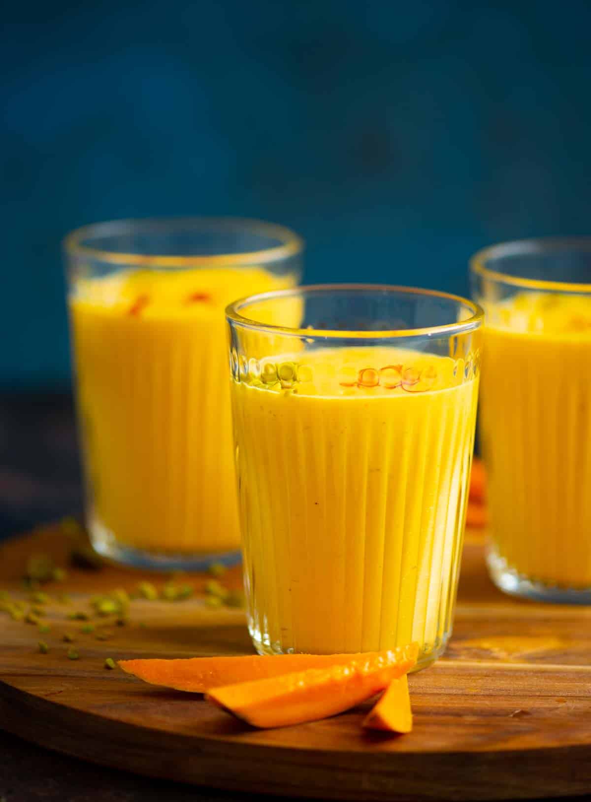 Mango clices in front of glasses of mango lassi