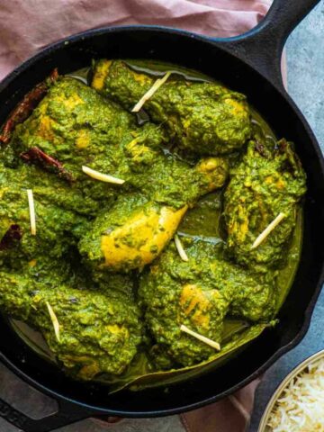saag chicken in a cast iron pan on a blue background