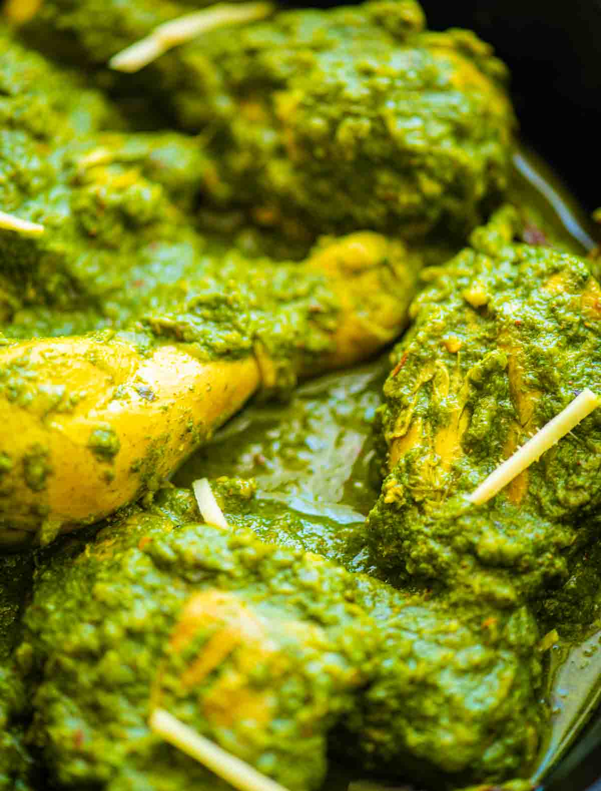 close up of green chicken curry garnished with ginger