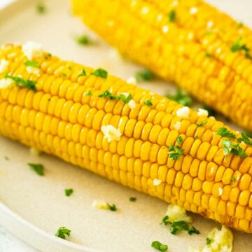 side view of corn on the cob on a cream plate