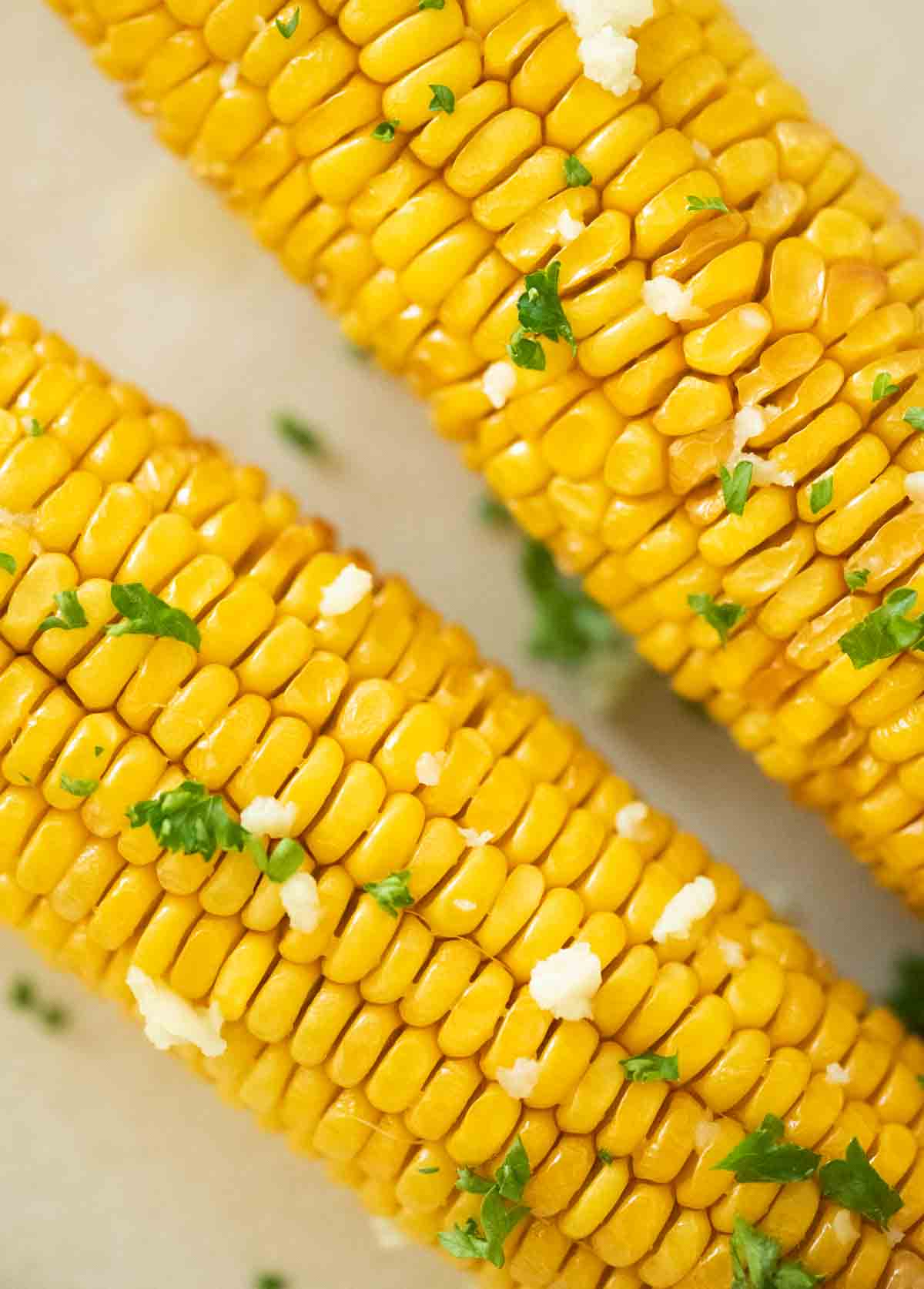 close up of corn on the cob with parsley and garlic
